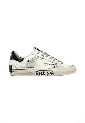 Sneaker bianco con tallone nero, lacci grigi e testo in stile graffiti che include "RECKLESS" e "DOUBLE TROUBLE" sul lato.