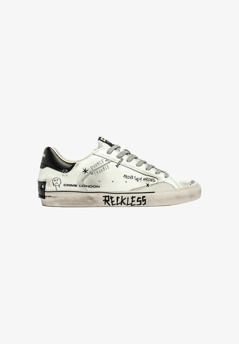 Sneaker bianco con tallone nero, lacci grigi e testo in stile graffiti che include "RECKLESS" e "DOUBLE TROUBLE" sul lato.