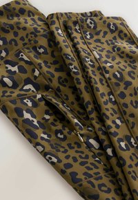 Õlilaine leopardimustriga spordipüksid, millel on tumesinine ja heledashall täpp. Omavad tõmblukke ja lamedat õmblust vastupidavuse tagamiseks.