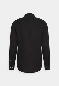 Chemise noire à manches longues en tissu doux, avec une coupe décontractée, un ourlet arrondi et des poignets boutonnés avec des boutons contrastants.