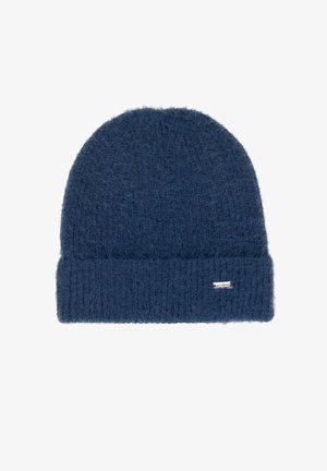 Gebreide muts in donkerblauw, met een zachte, pluizige textuur en een omgeslagen boord met een klein merkembleem aan de zijkant.