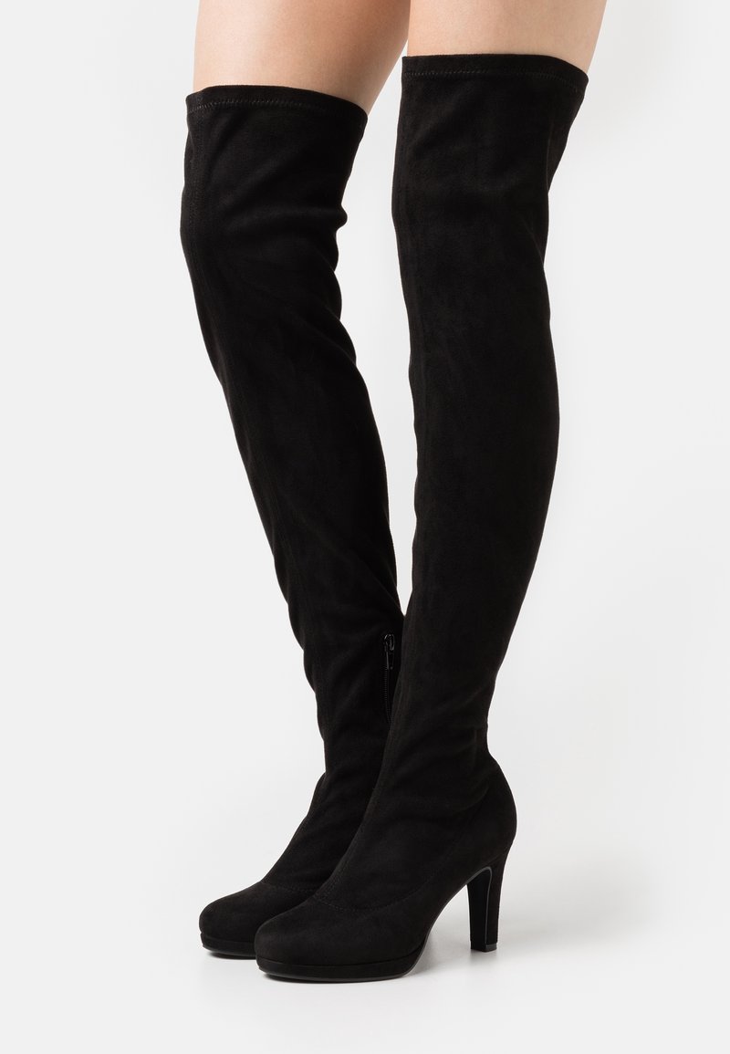 Botas negras por encima de la rodilla hechas de suave ante, con puntera redondeada, tacón alto y cremallera lateral para el cierre.