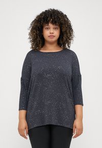 Sötét tengeri kék, hosszú ujjú felső, laza szabással, világos színekben pöttyös mintázattal és széles nyakkivágással. Puha, texturált anyag.