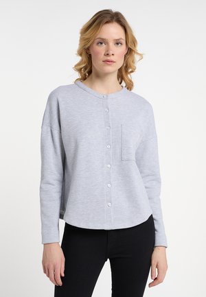 Světle šedá mikina s kulatým výstřihem, předním zapínáním na knoflíky, dlouhými rukávy a jednou kapsou na hrudi. Hladká textura a volný střih.