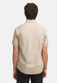 Korte mouw shirt in lichtbeige katoen met een klassieke kraag, een gladde textuur en een ronde zoom. Heeft een klein logo op de achterkant.