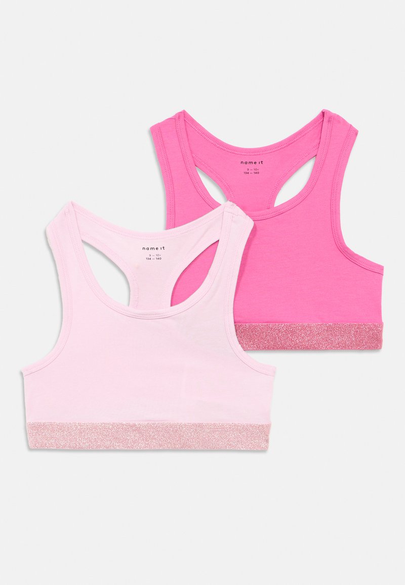 Twee racerback bralettes in lichtroze en felroze. Elk voorzien van een glinsterende roze band aan de onderkant. Gemaakt van zacht katoenen stof.