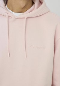 Sweat à capuche rose clair avec cordons, présentant un détail brodé "Perfenzione". Confectionné dans un matériau doux avec une texture lisse.