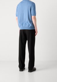 Haut tricoté bleu clair à manches courtes avec un ourlet côtelé, associé à un pantalon noir. Texture lisse et coupe décontractée, design minimaliste.