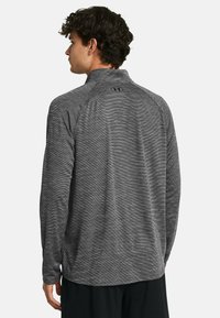 Gray long-sleeve top with a half-zip collar, featuring a subtle striped texture and logo on the upper back. Comfortable, athletic fit.