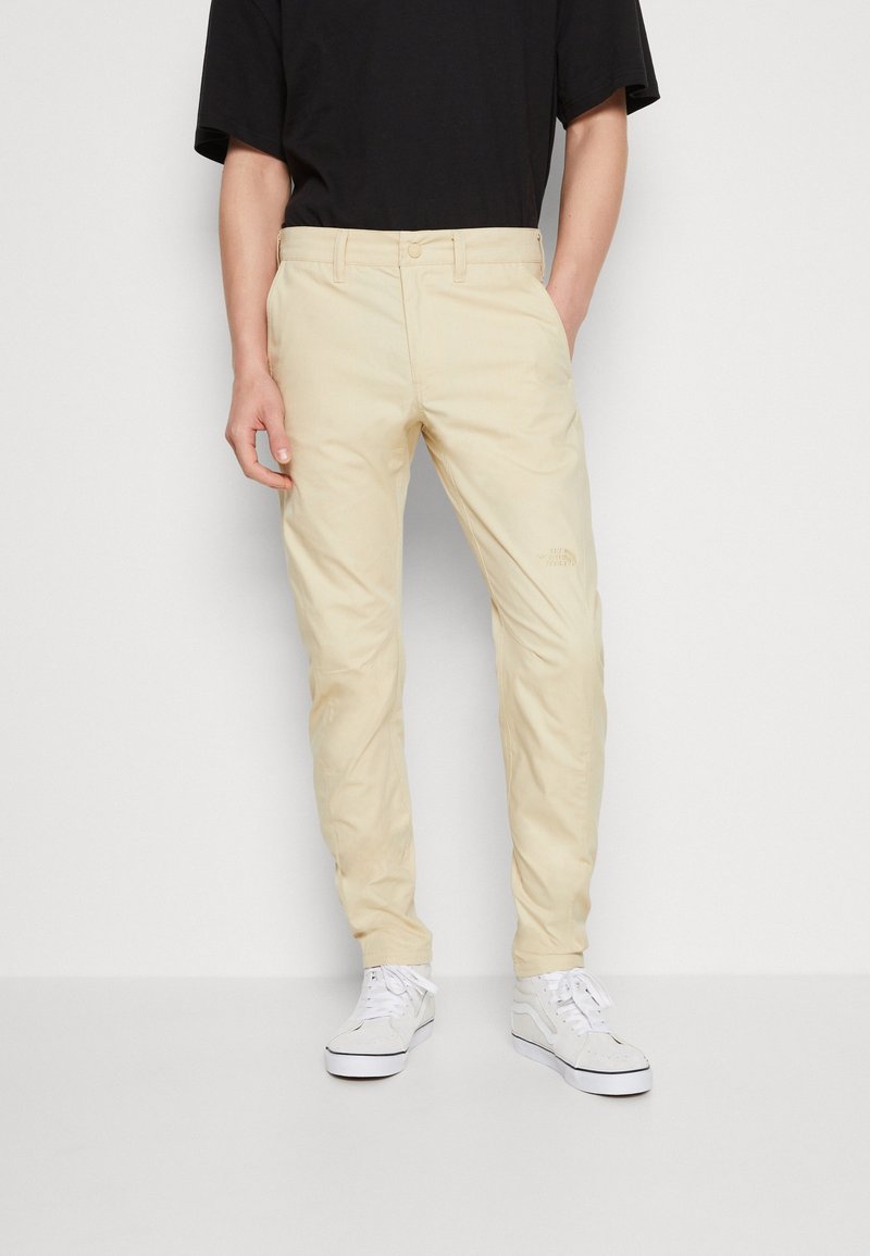 Beige, schmale Chinos aus einem glatten Material; verfügen über einen klassischen Knopfverschluss und ein dezentes Logodesign über der rechten Tasche.
