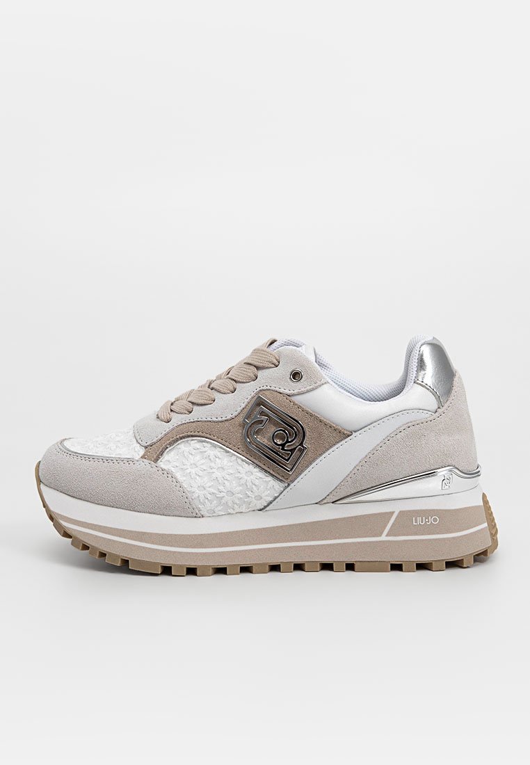 Sneaker di colore chiaro con una combinazione di materiali in suede e tessuto. Accentuata da dettagli metallici, motivo floreale e una suola spessa.