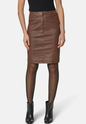 Bruine leren potloodrok met voornaden en een getailleerd ontwerp. Draagt met zwarte panty’s en enkellaarsjes. Gemakkelijke textuur.