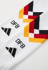 Meias de desporto brancas com padrões ousados em vermelho, amarelo e preto, com "DFB" e um logo de três riscas bordados perto do topo.