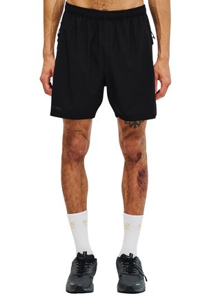 Black athletic shorts with an elastic waistband, lightweight fabric, side pockets, and length reaching mid-thigh. Worn with white socks and black sneakers.