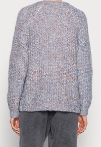 Przytulny, oversize'owy lawendowy sweter z dzianiny o fakturowanym wzorze, z wielobarwnymi drobinkami oraz prążkowanymi mankietami i dolnym obszyciem.