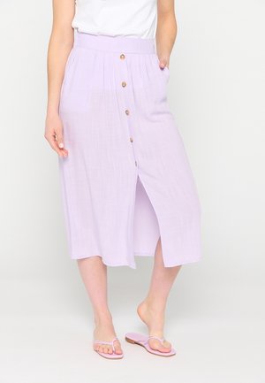 Lilla mellem-lang nederdel med høj talje, for-åbningsknapper, plisseringer, sidelommer og en let åben kant. Båret med lyserøde klipklapper.