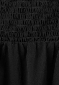 Tissu noir avec une ceinture élastique froncée et une texture froncée sous les lignes de couture.