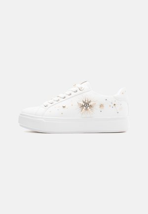 Hvid sneaker med platformssål, dekoreret med guld- og sølvstjerner og solstrålemotiver på siden.
