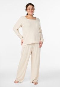 Beiges, geripptes Freizeitbekleidungs-Set mit einem langärmligen Oberteil mit eckigem Ausschnitt und locker sitzender Hose. Weiche Textur mit entspannter Silhouette.