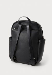 Μαύρο δερμάτινο σακίδιο με υφή, που διαθέτει ρυθμιζόμενους ιμάντες, λαβή στην κορυφή και μπροστινή τσέπη με φερμουάρ.