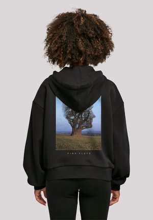 Black oversized hoodie featuring a graphic of a tree landscape on the back, with "PINK FLOYD" text in gold below the image.
