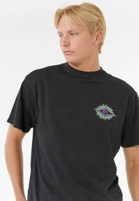 Sort bomulds T-shirt med korte ærmer, der har et farverigt, stiliseret øje-grafik på venstre bryst. Klassisk crew neck design.