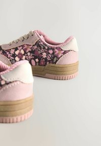Sneakers con motivo floreale rosa, con accenti in tessuto grigio e pelle, suola in gomma testurizzata e lacci rotondi. Presentano un collare imbottito.