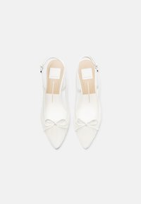 Λευκά παπούτσια slingback με μυτερή μύτη, υφασμάτινη υφή, μικρή λεπτομέρεια φιόγκου στο μπροστινό μέρος και ρυθμιζόμενο λουράκι με μεταλλική αγκράφα.