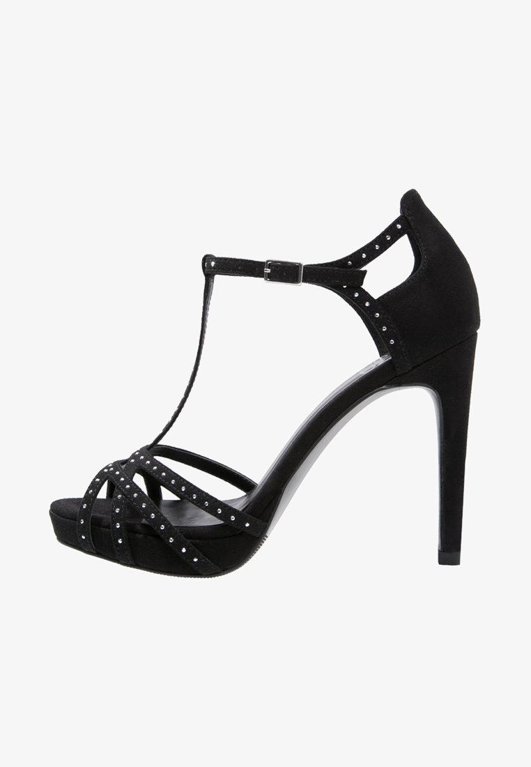 Sandale à talon haut noire avec design à bride en T, matériau en daim, brides croisées ornées de strass et talon brillant.
