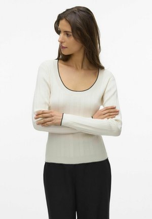 Haut blanc à manches longues à côtes avec un décolleté en forme de scoop et des détails en noir le long du col et des poignets. Matière douce et extensible.