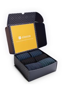 Doos met zes paar sokken in verschillende kleuren: blauw met blauwe strepen, zwart en donkergrijs met groene en rode strepen. Het kartonnen verpakkingsmateriaal heeft een gele binnenkant.