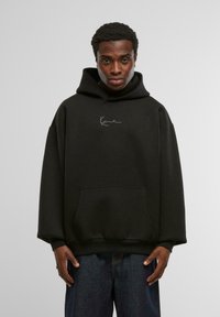 Must mustaga hoodie, millel ees tasku ja kapuuts, millel on nöörid. Rinnal on valge tikandiga logo. Pehme kangastekstuuri.