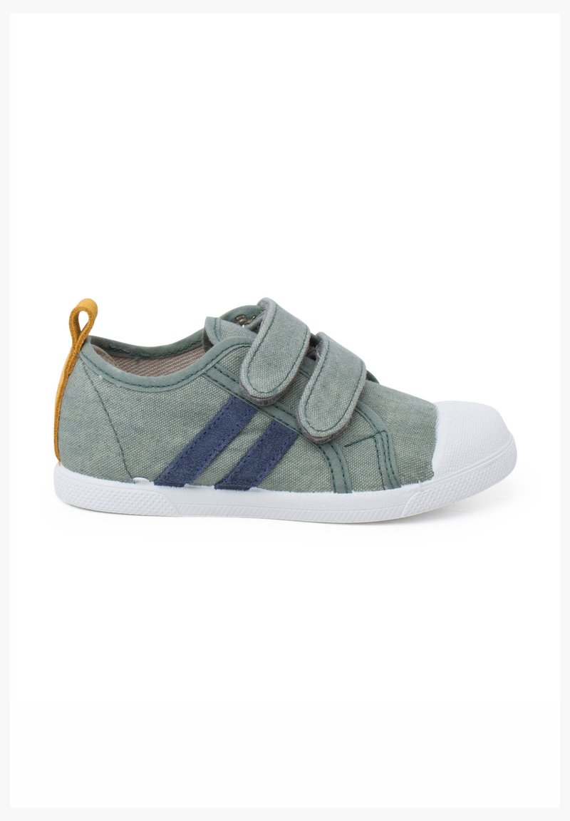 Scarpa in tela verde con punta in gomma bianca, strisce blu navy e cinturini in Velcro. Presenta una linguetta sul tallone gialla. Materiale testurizzato.
