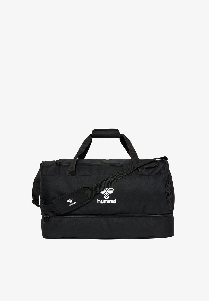 Sac de sport noir Hummel avec double poignée, bandoulière réglable et fermeture éclair du compartiment inférieur sur fond blanc.