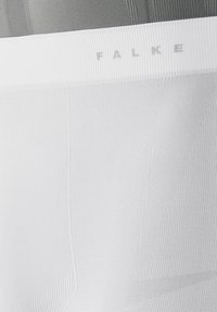 Calzini bianchi con texture a coste, dotati di un logo "FALKE" in grigio chiaro sul risvolto, che evidenziano un design elegante senza motivi.