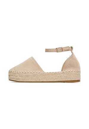 Espadrilla in camoscio beige con punta chiusa e cinturino alla caviglia, caratterizzata da una suola intermedia in juta intrecciata e una suola piatta in gomma. Design semplice e minimalista.