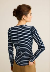Marinblå och vit randig långärmad topp med figurnära design och rundad halsringning, med en detalj med söm på baksidan. Materialet verkar vara ribbat.