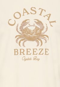 Graphique beige d’un crabe avec le texte « Coastal Breeze » au-dessus et en dessous, et « Oyster Bay » en cursive dessous, sur fond clair.