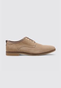 Zapatos de vestir de ante color tan con punta redondeada, diseño de cordones y un elegante borde de cuero marrón en contraste. Presentan una textura suave y mate.