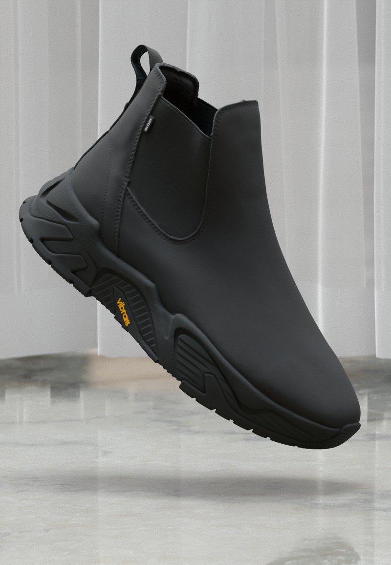 Black ankle boots with a sleek design, showcased against a light backdrop, highlighting their modern style and textured sole.