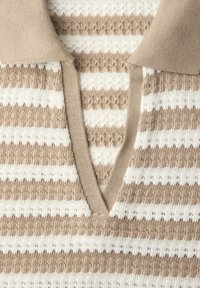 Beżowy i biały sweter w paski z dekoltem w serek oraz teksturowanym wzorem naprzemiennych poziomych pasów.