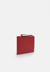Red rectangular clutch bag with textured surface and a wrist strap, standing upright on a white background.