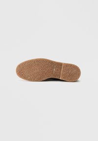 Czarna podeszwa buta z teksturowaną, gumowaną powierzchnią. Posiada zaokrąglony kształt i oznaczenie rozmiaru "41" z boku.