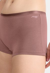 Brune Sloggi boyshorts lavet af blødt, elastisk materiale med en glat linning og diskrete logodetaljer. Tætsiddende, lavtaljet design.