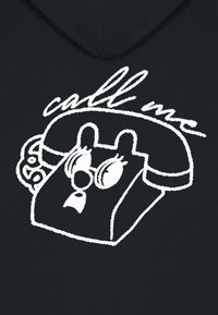 Hoodie noir arborant un graphique blanc d'un téléphone de dessin animé avec de grands yeux et un texte stylisé "appelle-moi" au-dessus.