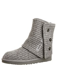 Bota de tobillo gris de punto con diseño doblado, tres botones decorativos en el lateral y parte superior de tela texturizada con suela de goma.