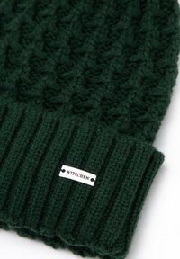 Groene gebreide muts met een geribde boord, voorzien van een gestructureerd patroon en een zilveren WITTCHEN-logo label. Gemaakt van zacht, warm materiaal.