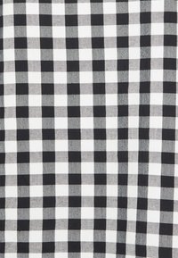 Tecido de pied-de-poule em preto e branco com padrão quadriculado, apresentando quadrados de tamanho uniforme num acabamento têxtil suave.