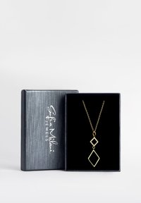 Guldsmykke med to geometriske pendanter, der har en diamantform og en mindre diamantaccent, præsenteret i en sort struktureret æske.