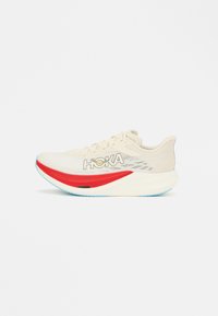 Αθλητικό παπούτσι με μπεζ πλέγμα στο επάνω μέρος, κόκκινη λεπτομέρεια στη σόλα, μπλε εξωτερική σόλα και λογότυπο "HOKA" στο πλάι. Ελαφρύς σχεδιασμός για απόδοση.